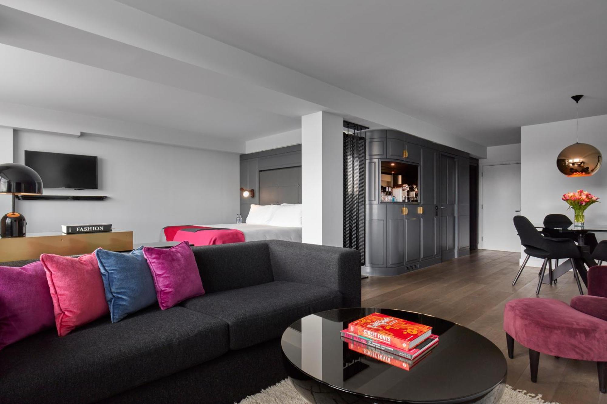 Hotel Sea Containers Londres Exterior foto The photo shows a modern and stylish living space. In the foreground, there is a dark gray sofa adorned with colorful pink and blue pillows. A circular coffee table sits in front of the sofa, with a few books stacked on it. 

In the background, there