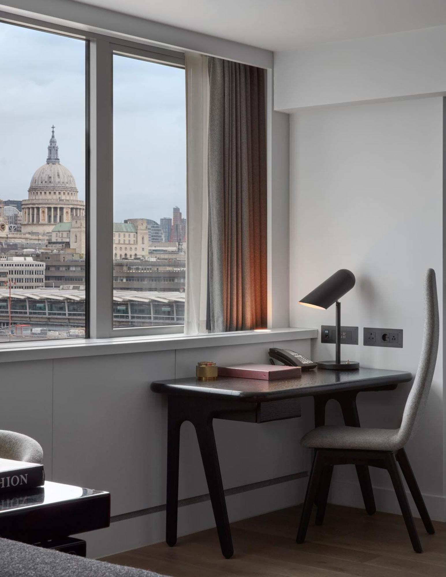 Hotel Sea Containers Londres Exterior foto The photo shows a modern office space with a view of a cityscape featuring a prominent dome, likely a historic building. There's a sleek desk with a lamp, a phone, and some stationery. The room has large windows allowing natural light to enter, and t