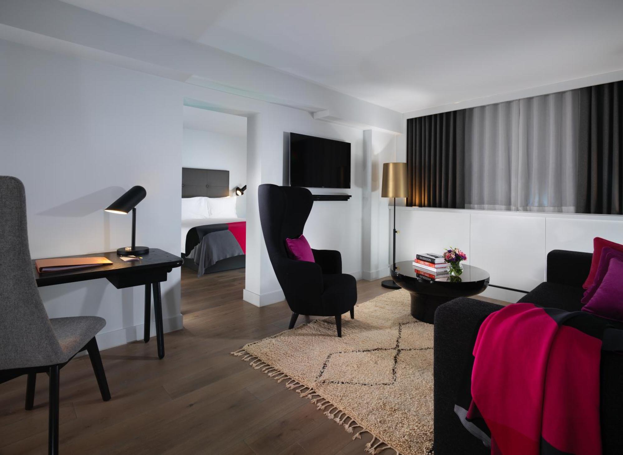 Hotel Sea Containers Londres Exterior foto The photo depicts a modern living space, likely part of a hotel room or suite. The room features:

- A comfortable seating area with two stylish armchairs in black, adorned with pink throw pillows.
- A small coffee table in the center, accompanied by