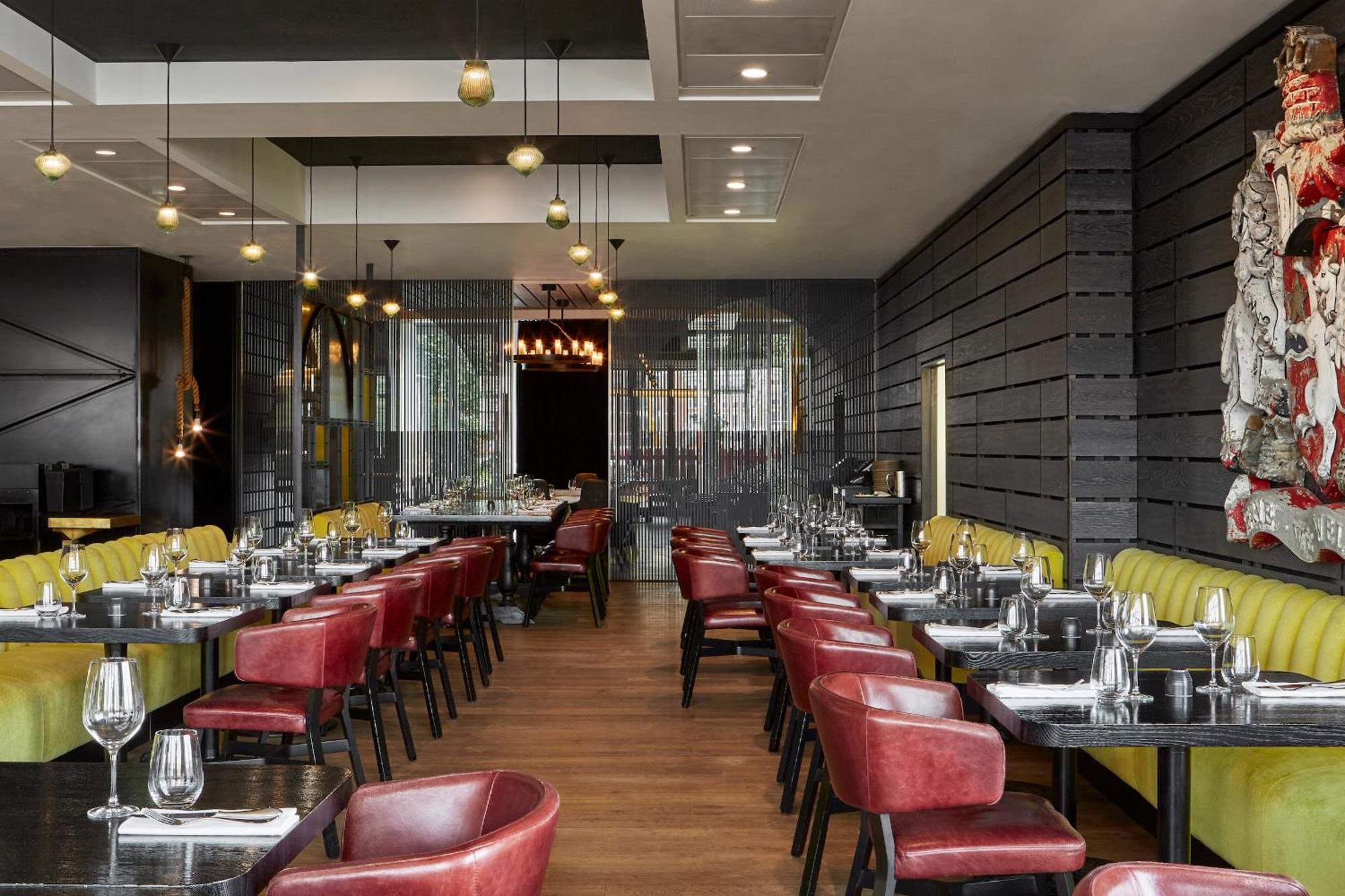 Hotel Sea Containers Londres Exterior foto The photo shows an interior of a modern restaurant. It features a combination of wooden and metallic elements, with a sleek design. The tables are set with cutlery and glassware, indicating readiness for diners. There are red and yellow upholstered c