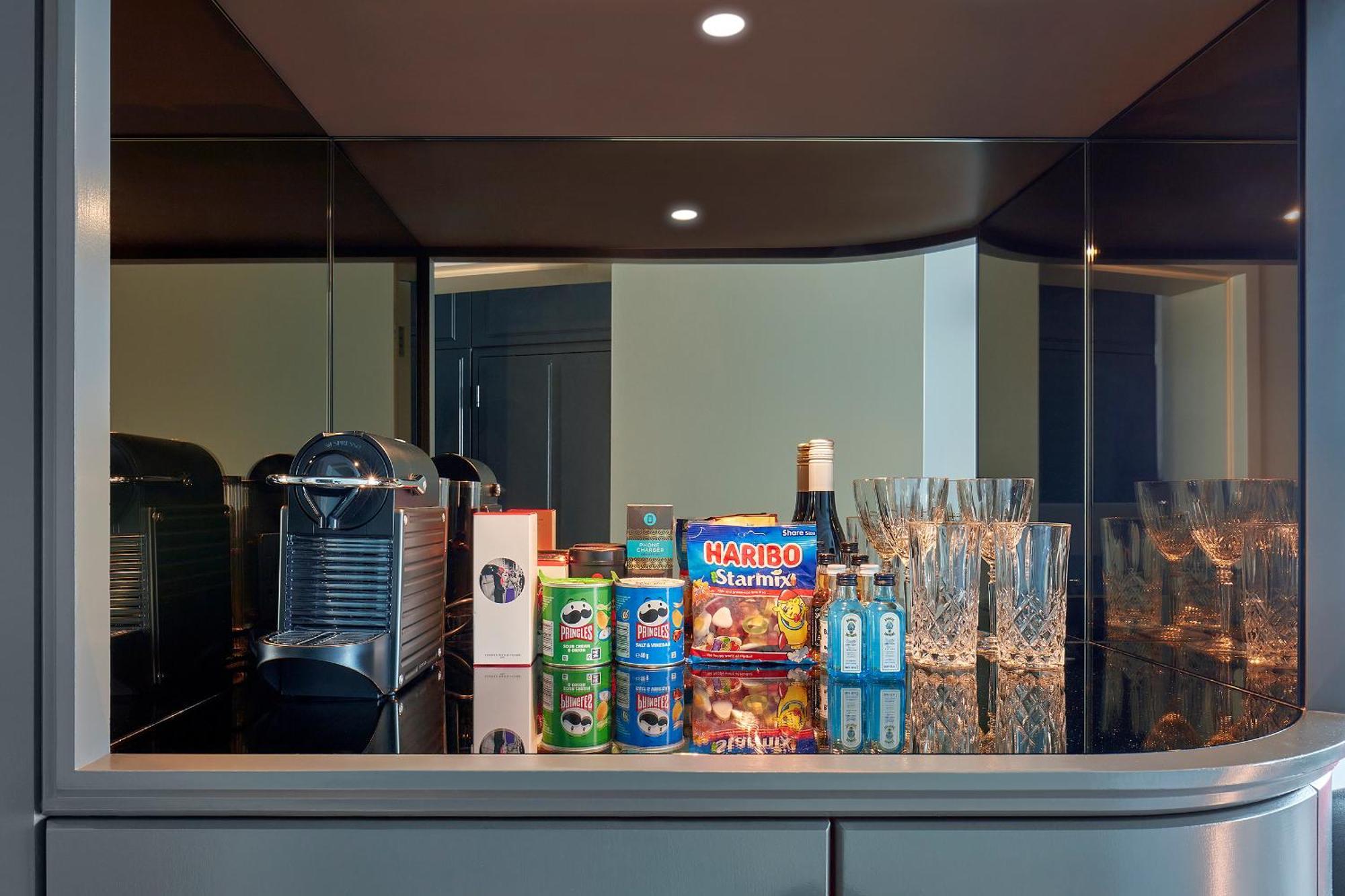 Hotel Sea Containers Londres Exterior foto The photo shows a sleek countertop, likely in a modern kitchen or bar area. On the left side, there is a silver coffee machine, possibly an espresso machine. Next to it, there are various beverages displayed in colorful cans, including what appears t