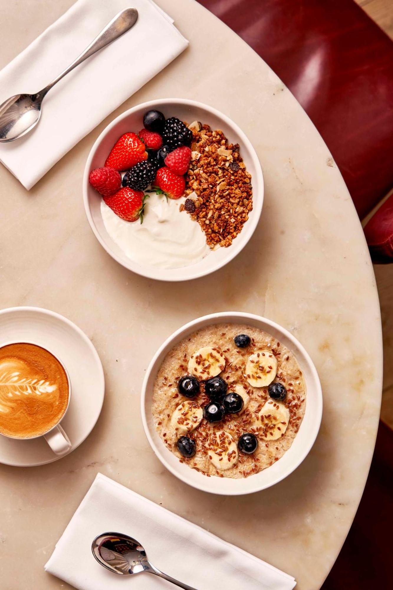 Hotel Sea Containers Londres Exterior foto The photo shows a delicious breakfast setting on a table. There are two bowls of food: one contains Greek yogurt topped with granola, mixed berries (like strawberries, blueberries, and blackberries), and another bowl features oatmeal topped with bana