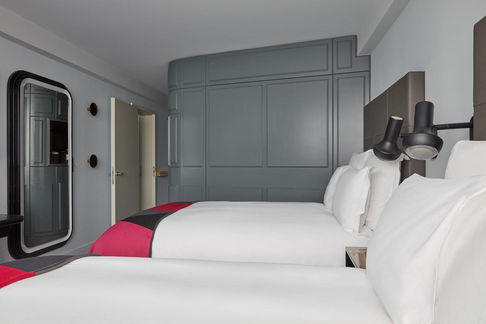 Hotel Sea Containers Londres Exterior foto The photo shows a hotel room with a contemporary design. It features two beds with white linens, complemented by vibrant pink and gray accents. The walls are painted in a soft gray color, creating a modern and minimalistic aesthetic. There is a styli