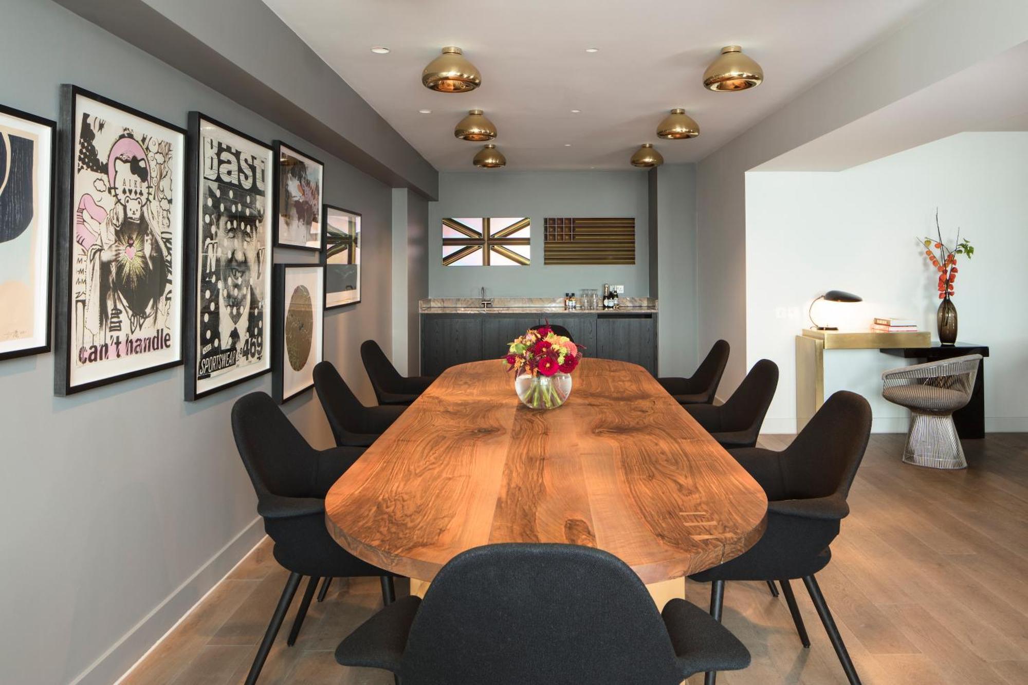 Hotel Sea Containers Londres Exterior foto The image depicts a modern dining or conference room. There is an elongated wooden table at the center, surrounded by black chairs. The walls are painted in a neutral gray color and adorned with several framed artworks, which include posters and abst