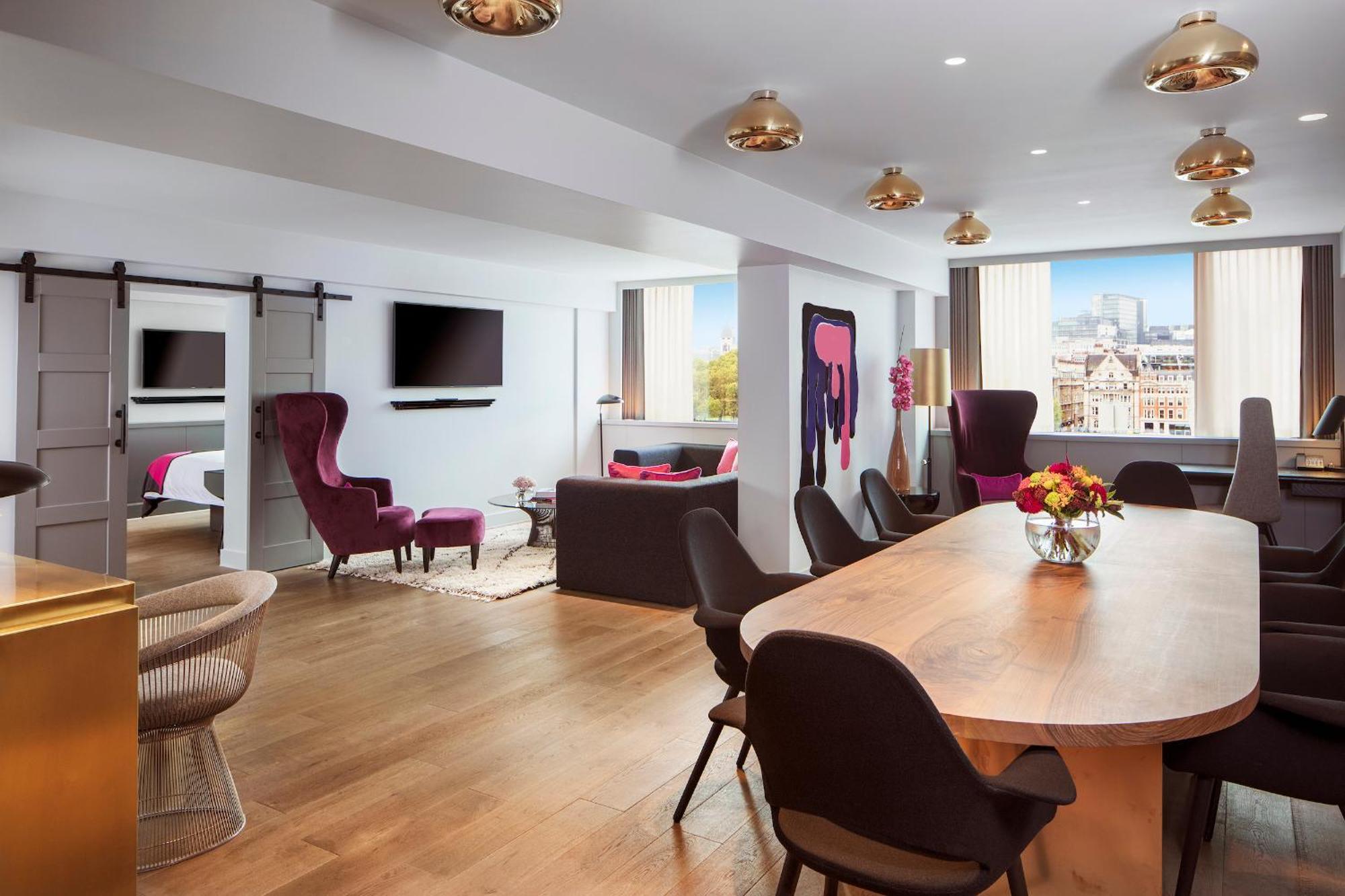 Hotel Sea Containers Londres Exterior foto The photo shows a modern and stylish lounge or living area. It features a spacious layout with wooden flooring and large windows letting in natural light. 

On one side, there are two distinct seating areas: a cozy dark-colored sofa facing a televisi