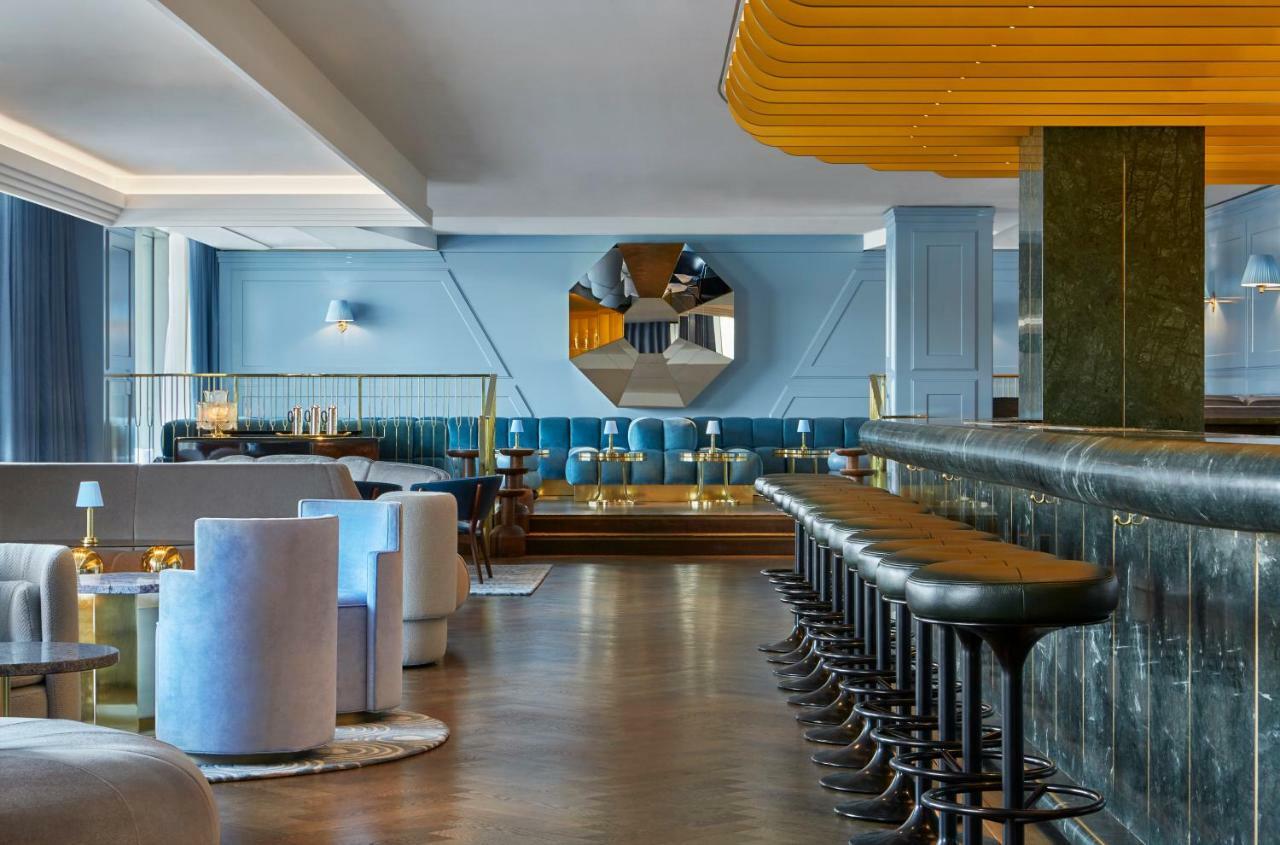 Hotel Sea Containers Londres Exterior foto The photo displays a modern and stylish bar or lounge area. The interior features a combination of soft blue walls and elegant furnishings. There are circular seating arrangements in light colors, creating a cozy atmosphere. A long bar counter made o
