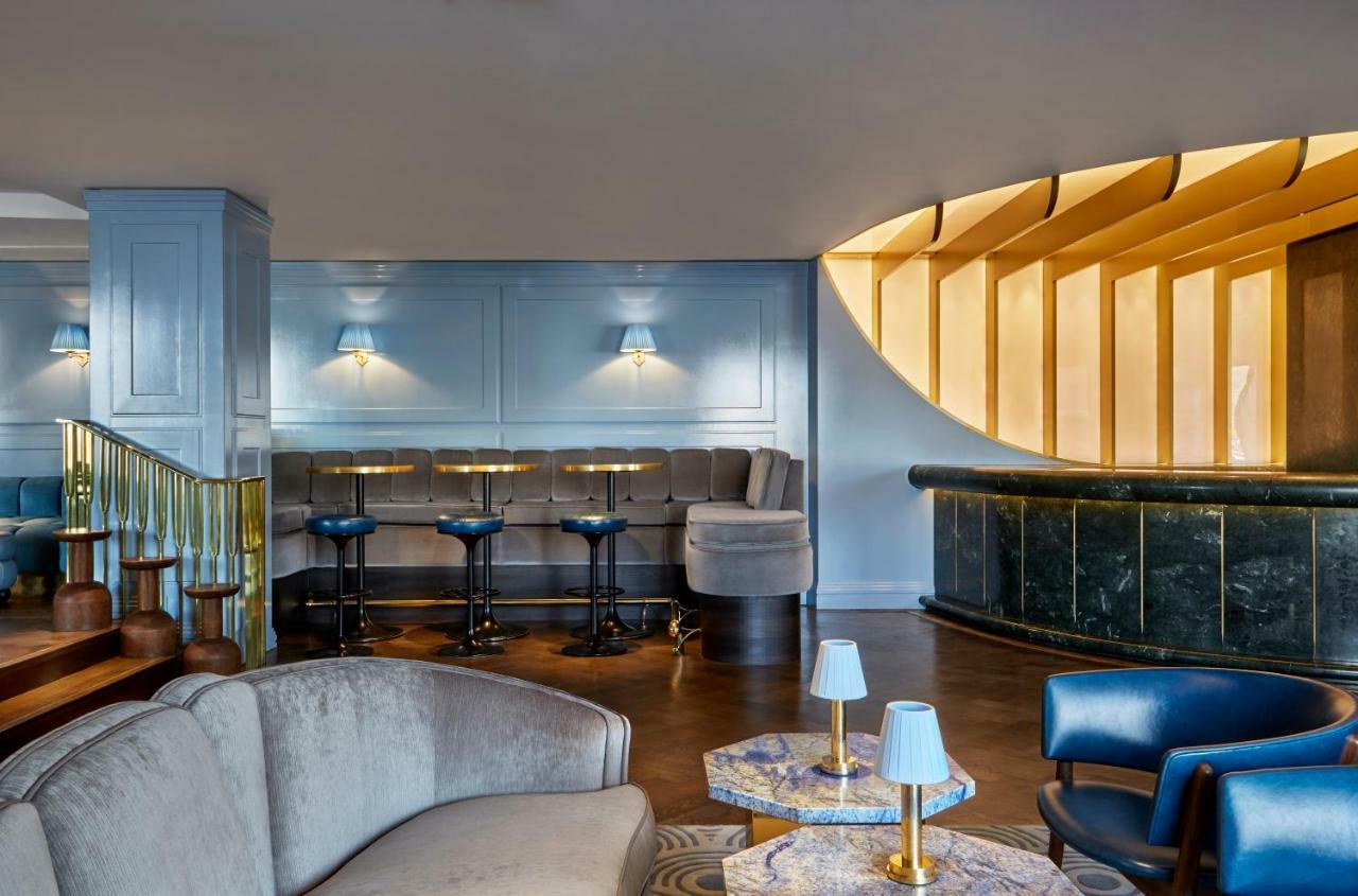 Hotel Sea Containers Londres Exterior foto The photo shows an elegantly designed interior space, likely a bar or lounge. The area features a modern seating arrangement with a mix of comfortable sofas and bar stools. The walls are painted in a soft blue color, complemented by wooden accents an